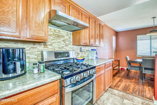 kitchen featuring extractor fan, hanging light fixtures, a textured ceiling, stainless steel range with gas cooktop, and backsplash