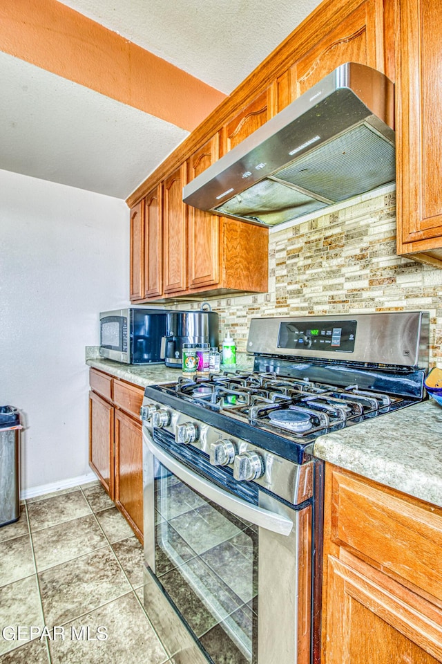 kitchen with backsplash, light tile patterned floors, range hood, and appliances with stainless steel finishes