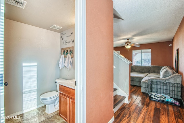 bathroom with ceiling fan, hardwood / wood-style floors, vanity, a textured ceiling, and toilet