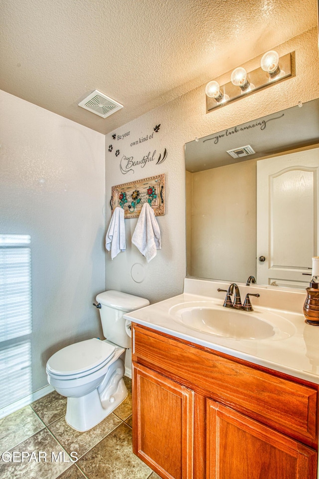 bathroom with vanity, tile patterned flooring, toilet, and a textured ceiling