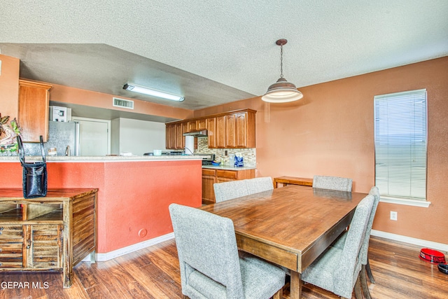 dining space featuring wood-type flooring and a textured ceiling