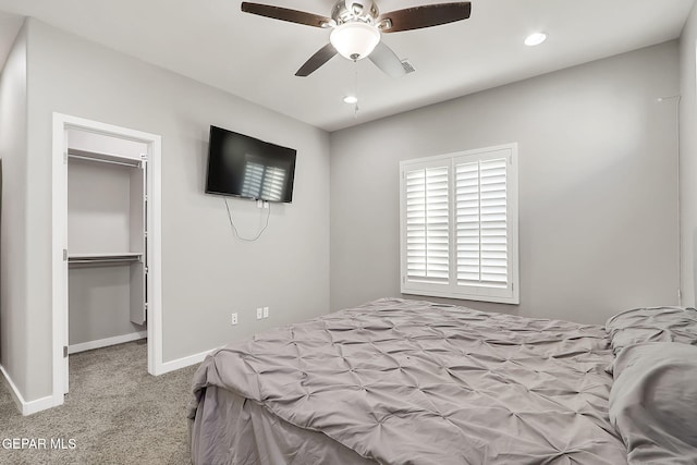 carpeted bedroom featuring a walk in closet, a closet, and ceiling fan