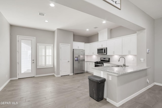 kitchen featuring sink, backsplash, stainless steel appliances, light stone counters, and white cabinets