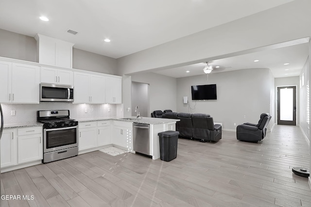 kitchen with sink, white cabinetry, kitchen peninsula, stainless steel appliances, and decorative backsplash