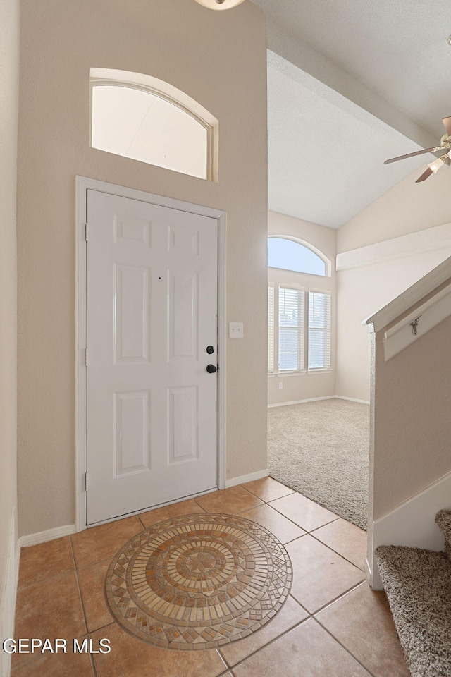 foyer with vaulted ceiling, light tile patterned floors, and ceiling fan