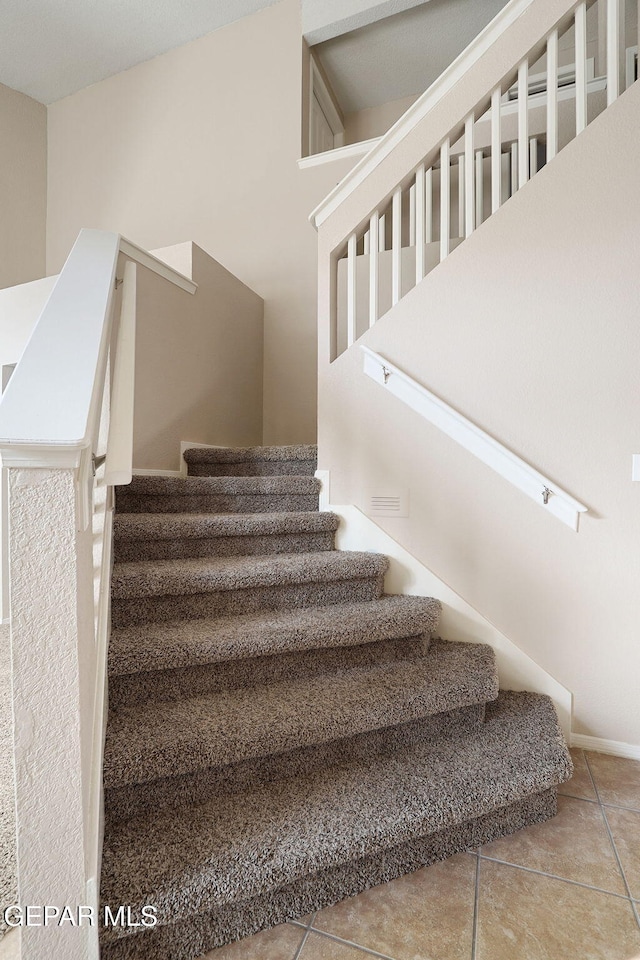 staircase featuring tile patterned flooring