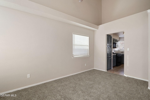 unfurnished room with a high ceiling and dark colored carpet