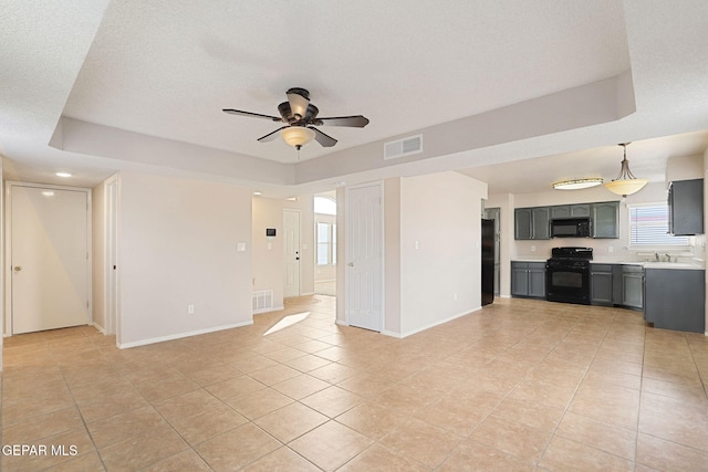 unfurnished living room with sink, light tile patterned floors, a textured ceiling, and ceiling fan