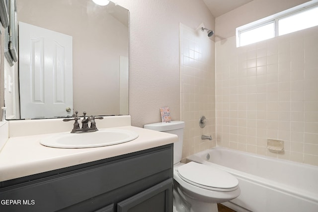 full bathroom with vanity, tiled shower / bath combo, and toilet