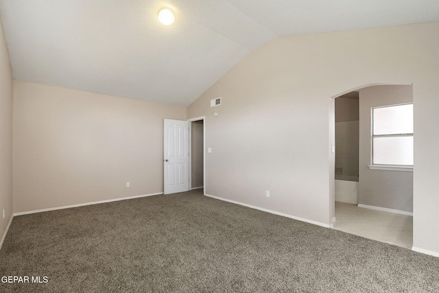 carpeted empty room with vaulted ceiling