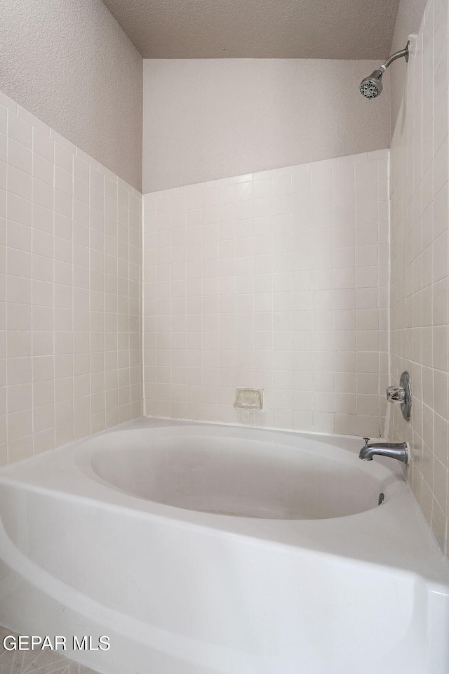 bathroom featuring tiled shower / bath combo and a textured ceiling