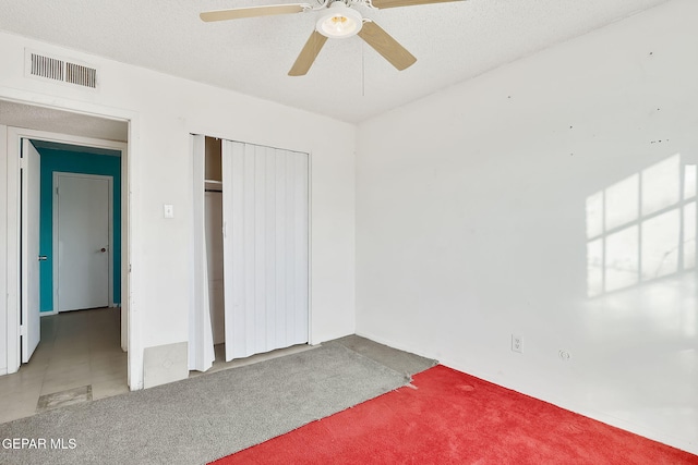 unfurnished bedroom featuring ceiling fan, a closet, carpet flooring, and a textured ceiling