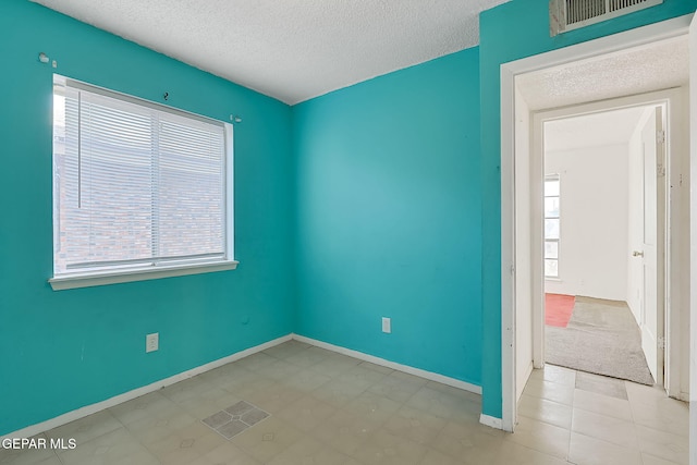 empty room featuring a textured ceiling and a wealth of natural light