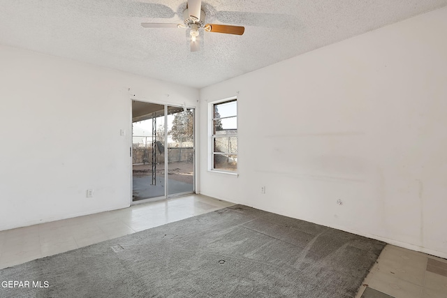 spare room featuring ceiling fan, light colored carpet, and a textured ceiling