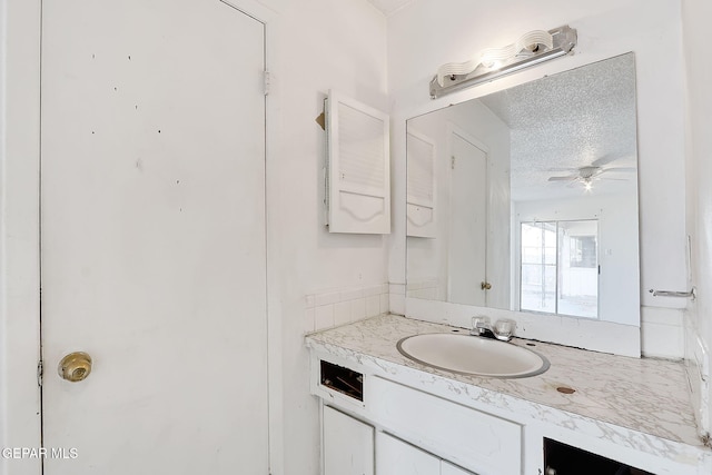 bathroom featuring ceiling fan, vanity, and a textured ceiling