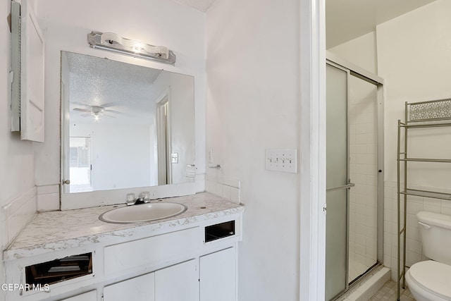 bathroom with vanity, toilet, a shower with door, and a textured ceiling