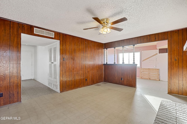 spare room featuring ceiling fan, a textured ceiling, and wood walls