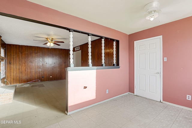 spare room featuring wooden walls and ceiling fan