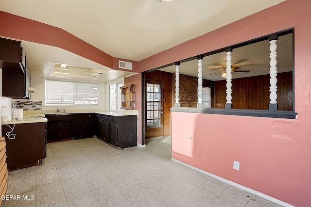 kitchen with dark brown cabinetry, sink, a tray ceiling, and ceiling fan