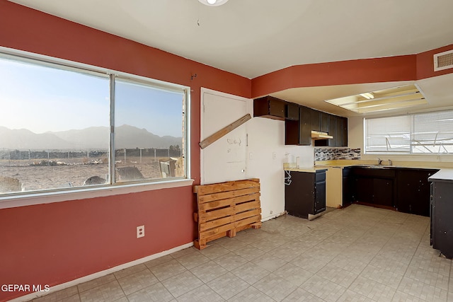 kitchen with dark brown cabinetry, a mountain view, backsplash, and sink