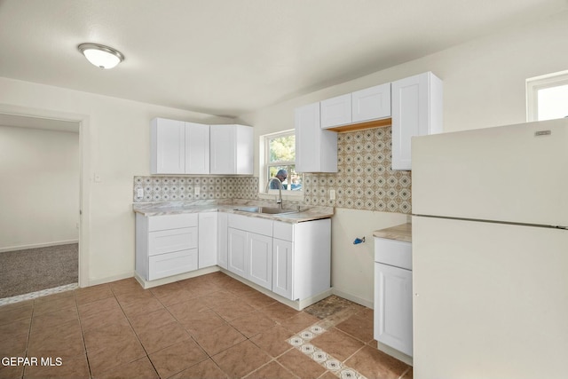 kitchen featuring sink, light tile patterned floors, white refrigerator, tasteful backsplash, and white cabinets