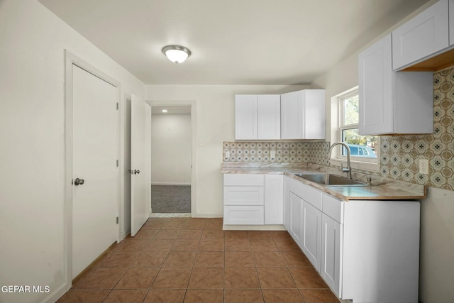 kitchen with light tile patterned flooring, sink, white cabinets, and decorative backsplash