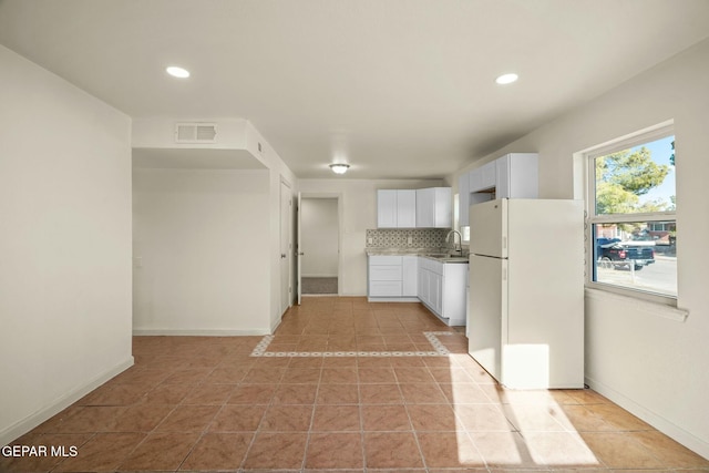 kitchen with sink, white cabinetry, tasteful backsplash, light tile patterned flooring, and white fridge