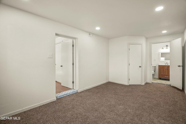 unfurnished bedroom with sink, light colored carpet, and ensuite bath