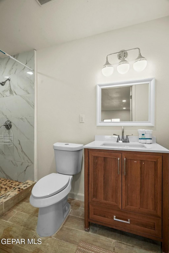 bathroom with vanity, toilet, and a tile shower