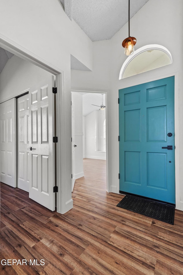 entryway featuring ceiling fan, dark wood-type flooring, and a textured ceiling