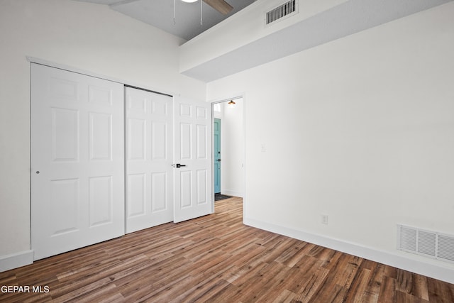 unfurnished bedroom featuring hardwood / wood-style floors, vaulted ceiling, a closet, and ceiling fan