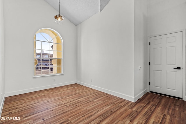 unfurnished room with dark wood-type flooring, high vaulted ceiling, and a textured ceiling