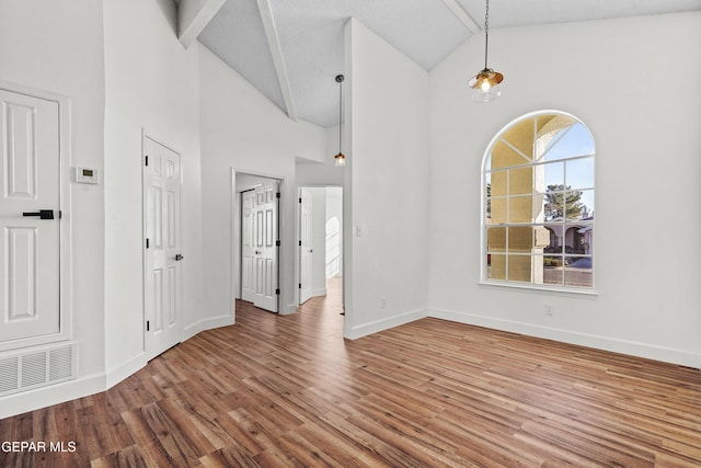 empty room with hardwood / wood-style flooring and high vaulted ceiling