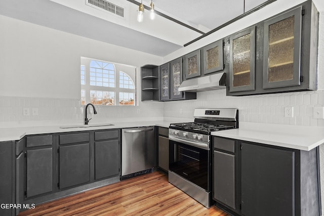 kitchen featuring stainless steel appliances, light hardwood / wood-style floors, sink, and backsplash