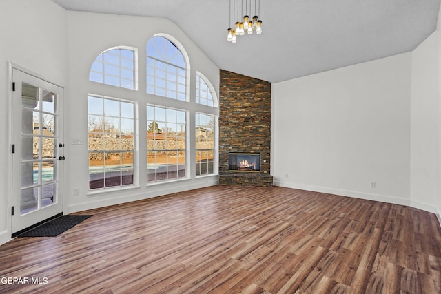 unfurnished living room featuring hardwood / wood-style floors, a fireplace, high vaulted ceiling, and a chandelier