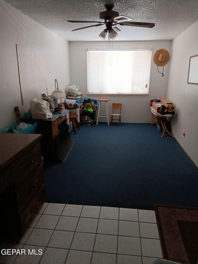 interior space with tile patterned flooring, ceiling fan, and a textured ceiling