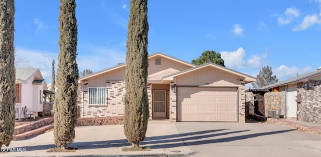 single story home with a garage and central AC unit