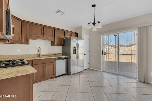 kitchen with sink, light tile patterned floors, appliances with stainless steel finishes, an inviting chandelier, and decorative light fixtures