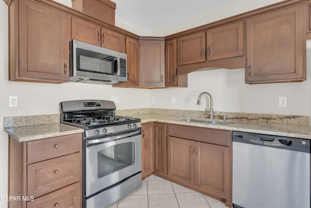 kitchen featuring light stone counters, stainless steel appliances, sink, and light tile patterned floors