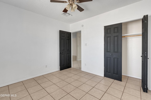 unfurnished bedroom with light tile patterned floors, a closet, a textured ceiling, and ceiling fan