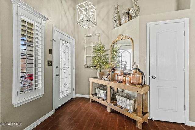 doorway with a notable chandelier and dark hardwood / wood-style flooring