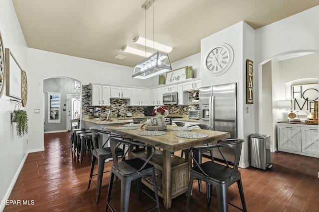 kitchen featuring pendant lighting, backsplash, stainless steel appliances, dark hardwood / wood-style floors, and white cabinets