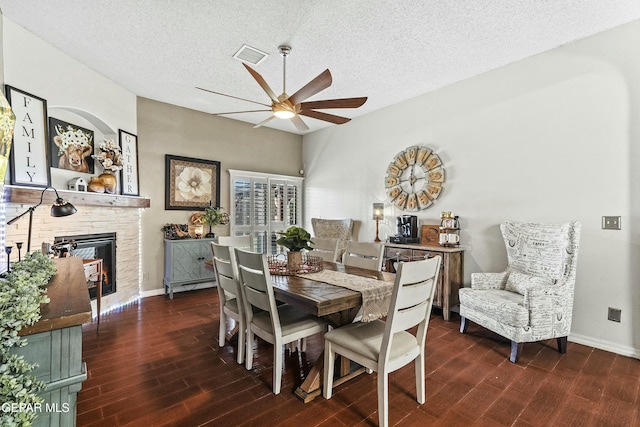 dining space featuring ceiling fan, dark hardwood / wood-style floors, a textured ceiling, and a fireplace