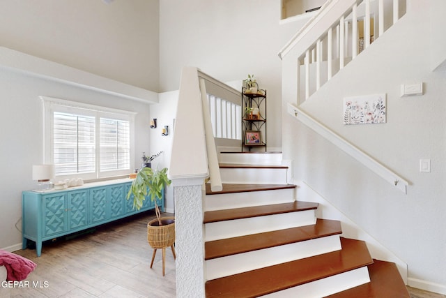 staircase featuring a high ceiling and hardwood / wood-style flooring