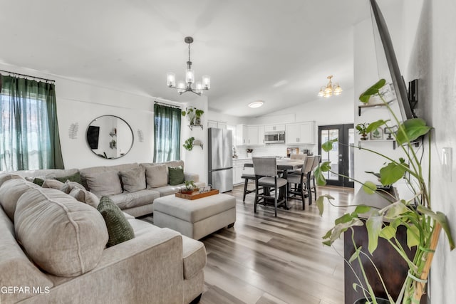 living room featuring lofted ceiling, light wood-type flooring, and a chandelier