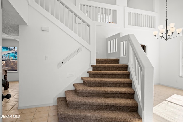 stairs with tile patterned flooring, a high ceiling, and a chandelier