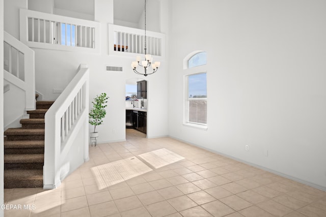 entryway with a notable chandelier, light tile patterned floors, and a towering ceiling