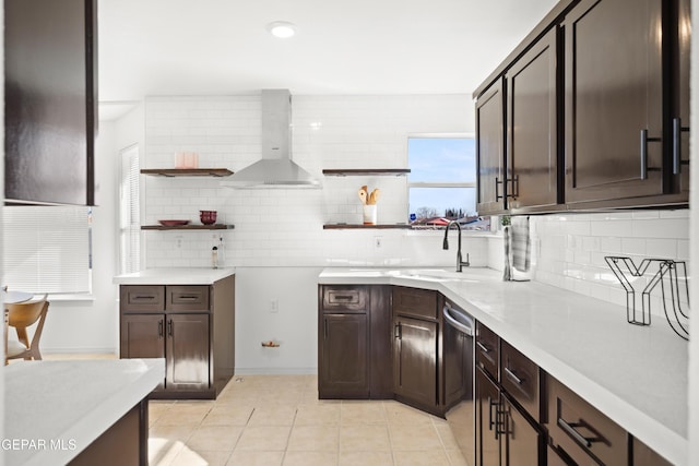 kitchen featuring dark brown cabinetry, wall chimney exhaust hood, sink, dishwasher, and decorative backsplash