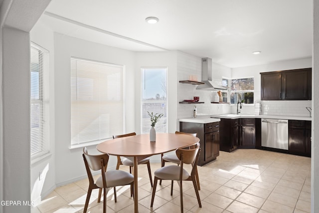 kitchen featuring dishwasher, backsplash, dark brown cabinetry, and wall chimney exhaust hood