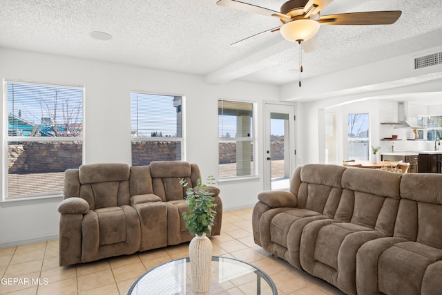 tiled living room featuring ceiling fan, plenty of natural light, and a textured ceiling